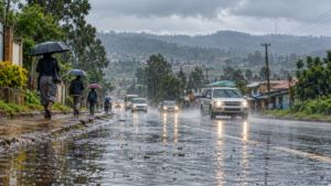 Pedestrians carrying umbrellas beside a wet road during rainfall in a Kenyan setting.